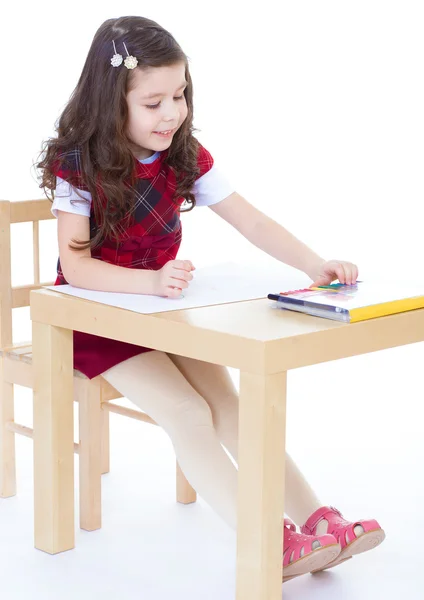 Niña está dibujando usando lápices de color mientras está sentada en tabl —  Fotos de Stock