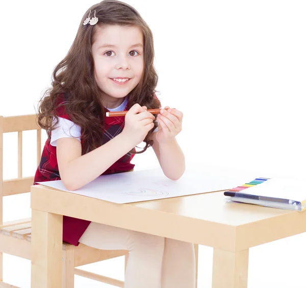 Маленька дівчинка малює, використовуючи кольорові олівці, сидячи за табло — стокове фото