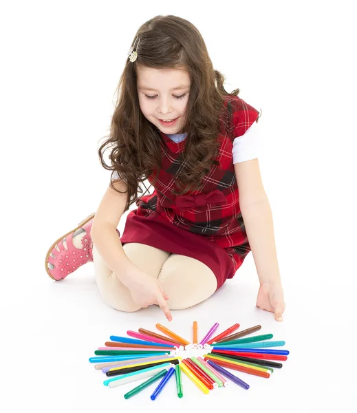 Katta oturan ve renkli kalemler ile oynarken küçük kız. — Stok fotoğraf