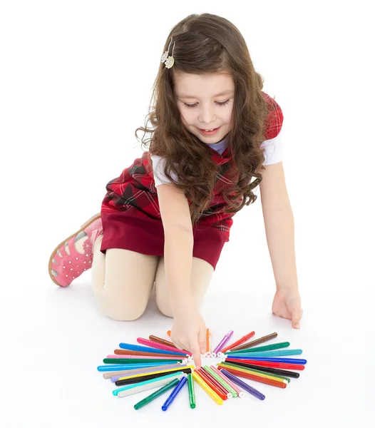 Meisje, zittend op de vloer en het spelen met gekleurde pennen. — Stockfoto