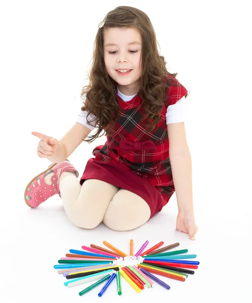 Meisje, zittend op de vloer en het spelen met gekleurde pennen. — Stockfoto