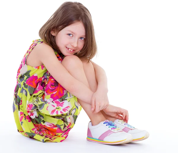 Hübsches junges Mädchen sitzt und umarmt ihre Knie. — Stockfoto