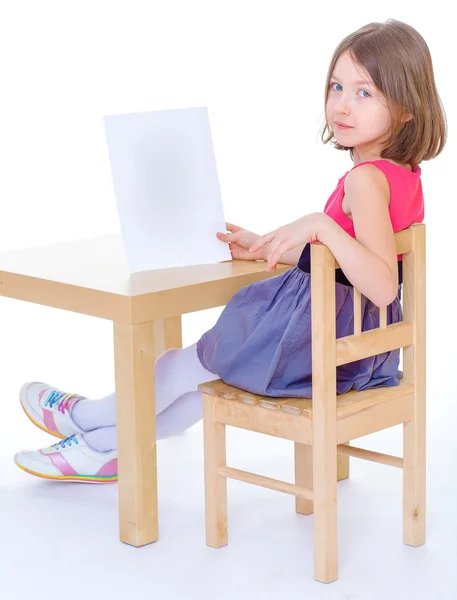 Meisje schoolmeisje zit aan een tafel — Stockfoto