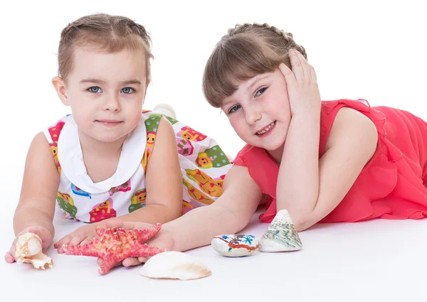 Two little girls are playing and shells and starfish. — Stock Photo, Image