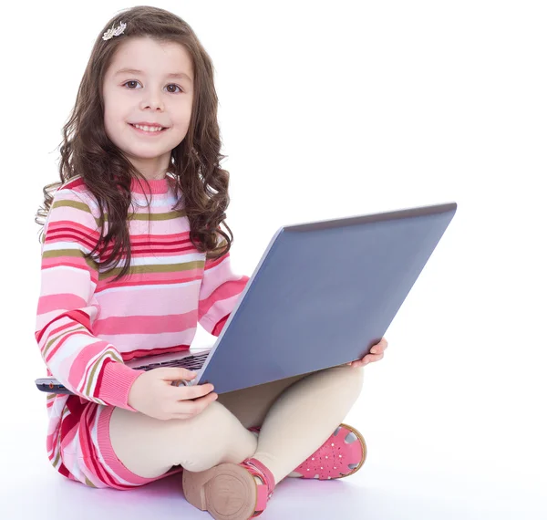 Bir dizüstü bilgisayar ile katta oturan küçük kız. — Stok fotoğraf