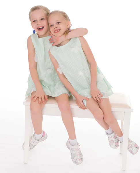Irmãs bonitos se divertindo sentado em uma cadeira . — Fotografia de Stock
