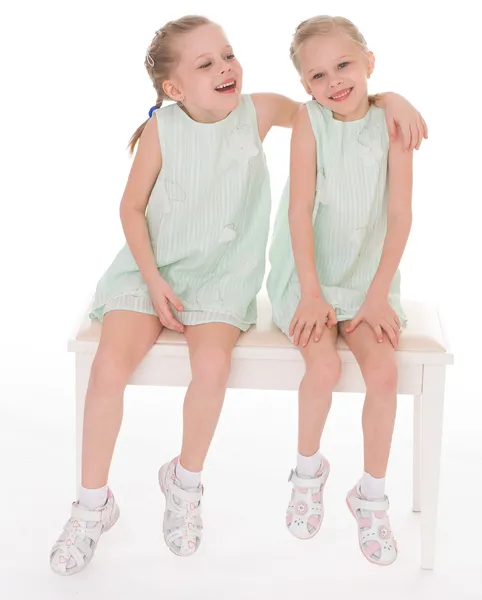 Cute sisters having fun sitting on a chair. — Stock Photo, Image