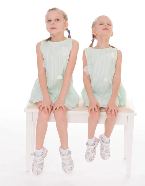 Cute sisters having fun sitting on a chair. Stock Photo
