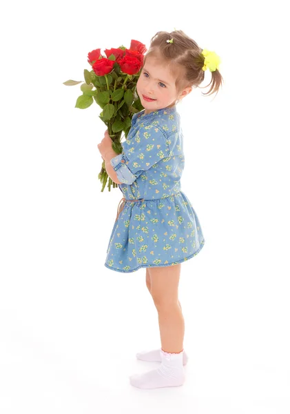 Charmant klein meisje houdt van een boeket van rode rozen. — Stockfoto