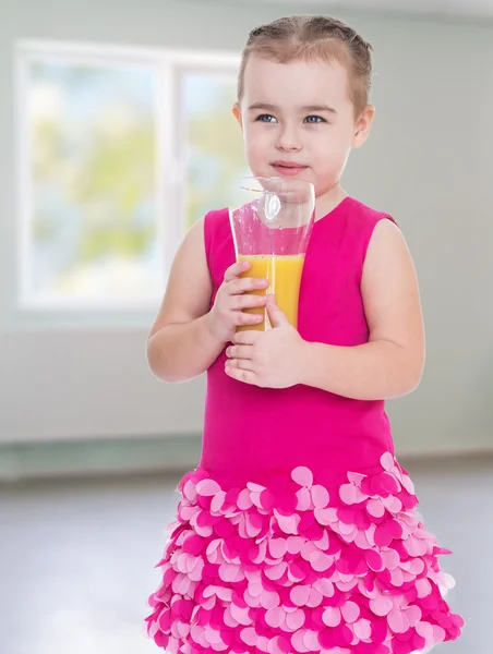 Liten flicka med ett glas apelsinjuice. — Stockfoto