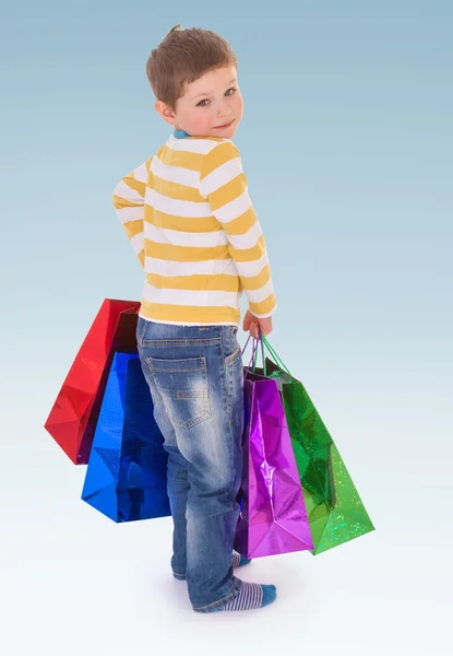 Мальчик с большими цветными пакетами — стоковое фото