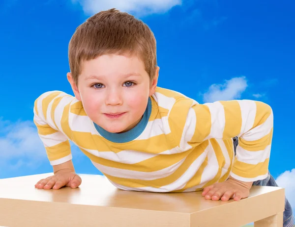 Kleine jongen liggend op zijn buik op de children's tabel — Stockfoto