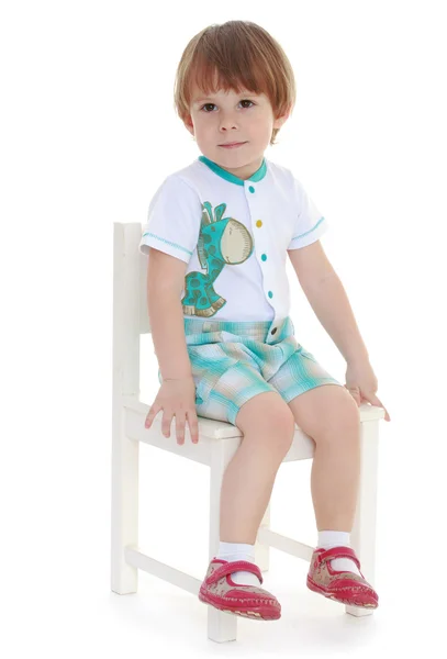 Μικρό αγόρι κάθεται σε μια καρέκλα. — Φωτογραφία Αρχείου