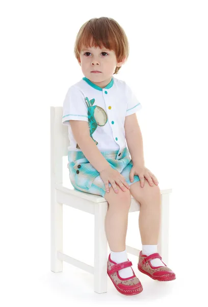 Malý chlapec sedí na židli. — Stock fotografie