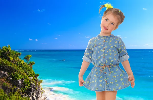 Bambina in un abito blu corto su uno sfondo di mare . — Foto Stock