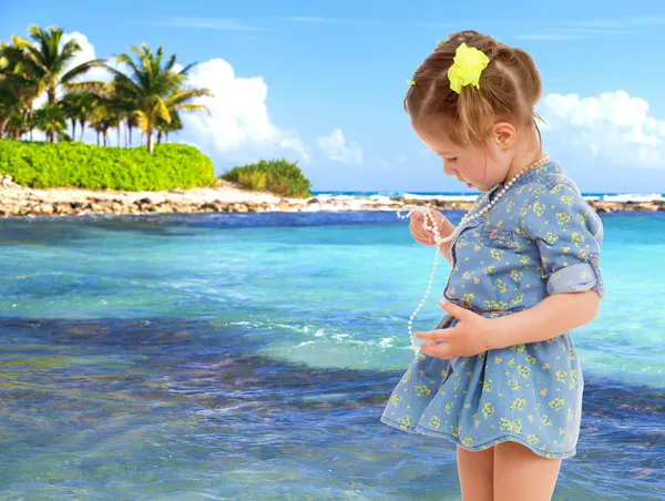 Little girl in a short blue dress on a sea background. — Stock Photo, Image