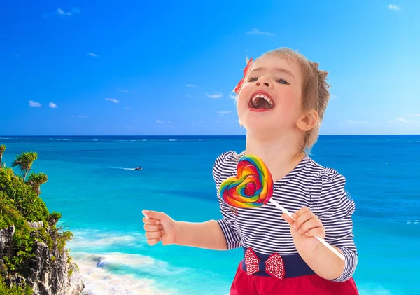 Mädchen mit Süßigkeiten auf dem Hintergrund des Meeres. — Stockfoto