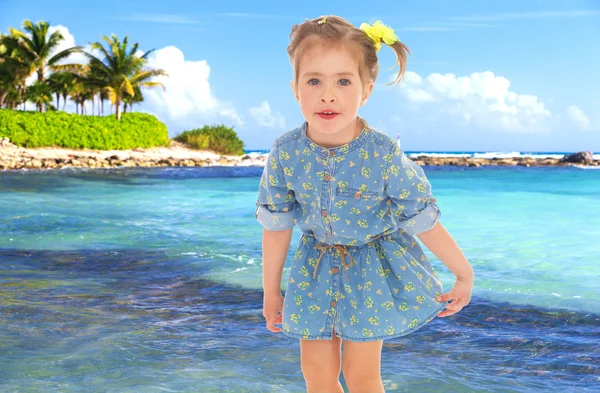 Bambina in un abito blu corto su uno sfondo di mare . — Foto Stock