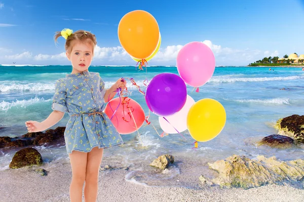Little girl in a short blue dress on a sea background. — Stock Photo, Image