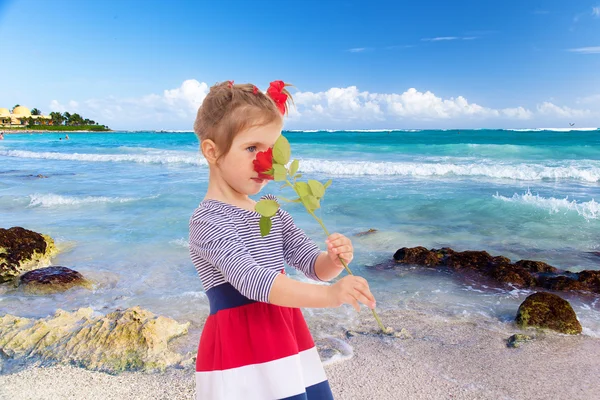 Meisje ruiken een roos op het strand. — Stockfoto