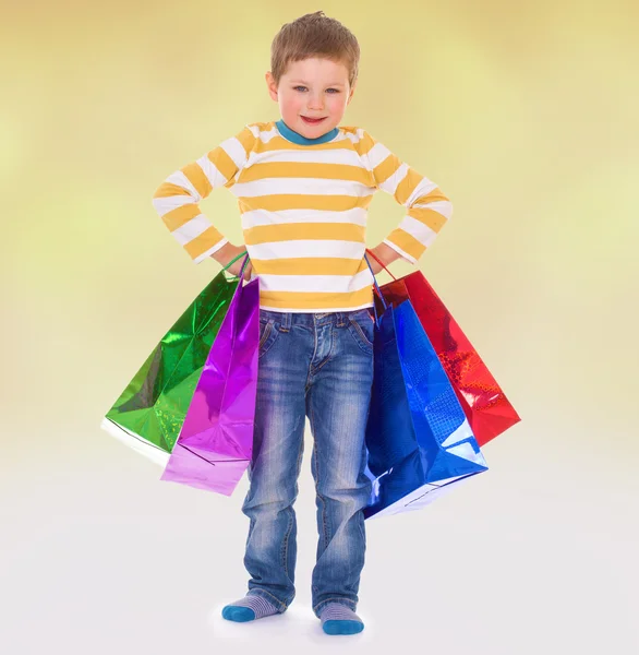 Little boy in colorful bags goes to the store. — Stock Photo, Image