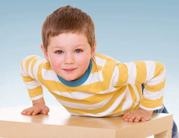 De jongen klom op de tabel. — Stockfoto