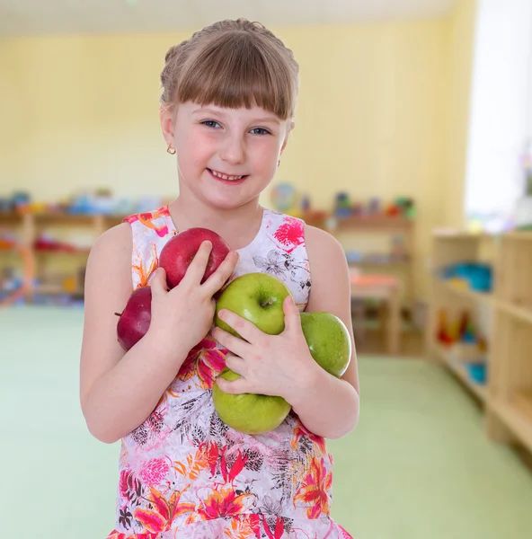 Positive girl holding a lot of apples. — Stock Photo, Image