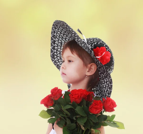 Flicka i en hatt med en bukett blommor. — Stockfoto