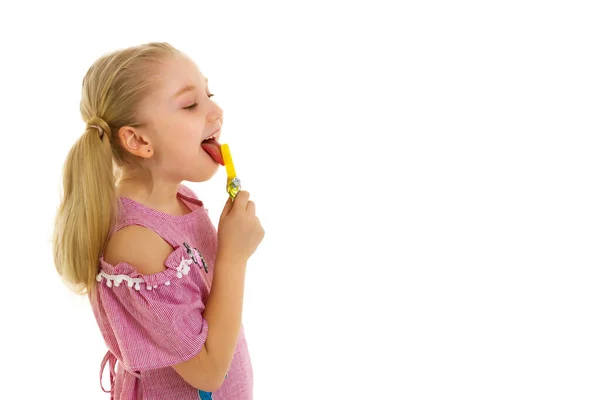 Roztomilá holčička olizuje bonbón. — Stock fotografie