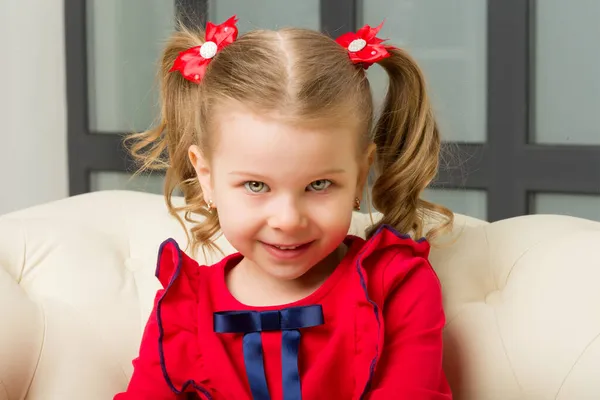 Linda niña rubia sentada en un sillón cómodo — Foto de Stock