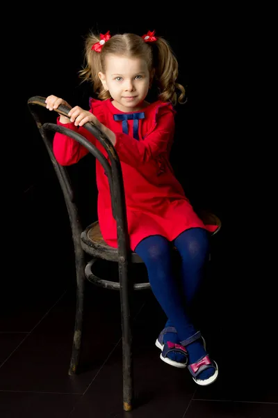 Cute blonde little girl sitting on wooden chair — Stock Photo, Image