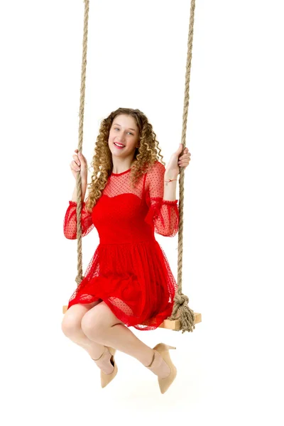 Kırmızı elbiseli güzel kız salıncakta sallanıyor — Stok fotoğraf