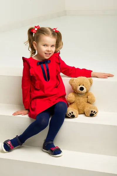 Little girl sitting on stairs with teddy bear — Stock Photo, Image