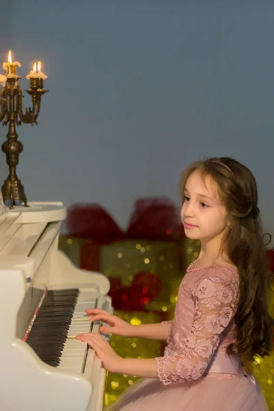 Hermosa chica tocando el piano y mirando velas ardientes —  Fotos de Stock