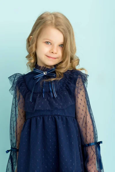 Милая маленькая девочка позирует в красивом голубом платье — стоковое фото