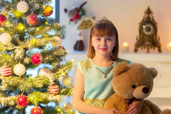 テディベアの女の子がクリスマスツリーの近くのソファに座っている. — ストック写真