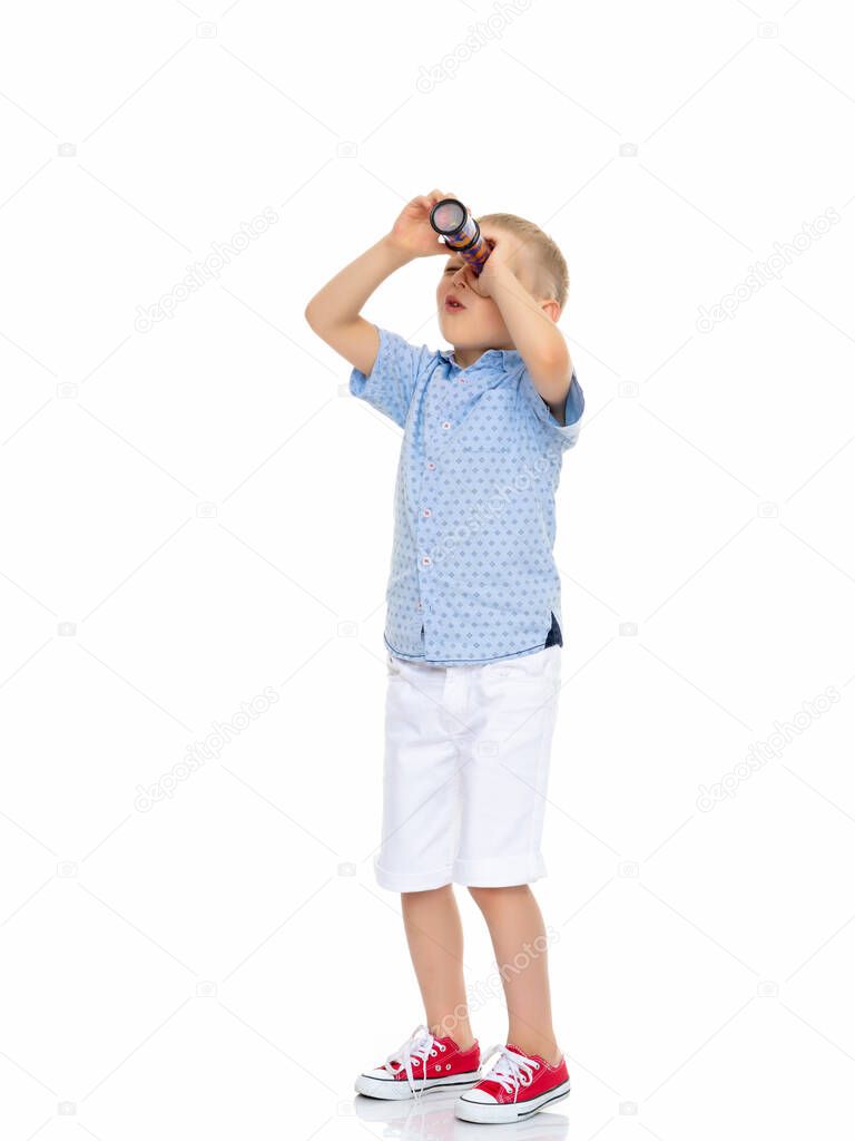 A little boy looks through a telescope or kaleidoscope.