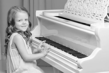 Küçük kız piyano, siyah ve beyaz fotoğraf çalış.