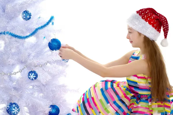 Uma menina está decorando uma árvore de Natal . — Fotografia de Stock