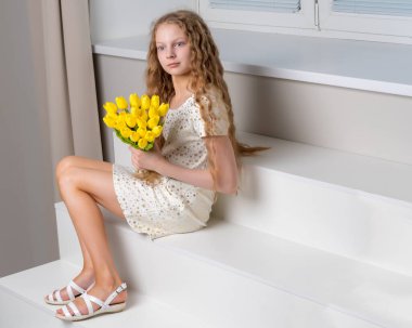 Lale bir buket ile küçük bir kız merdivende oturuyor.