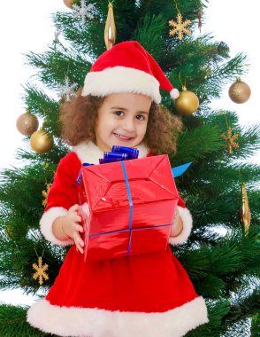 Elinde bir hediye ile Noel ağacının yanında küçük kız