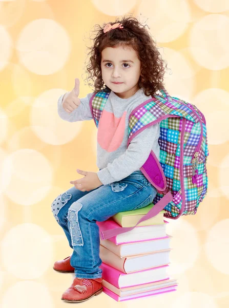 Little girl sitting on stack of books — Stock Photo, Image