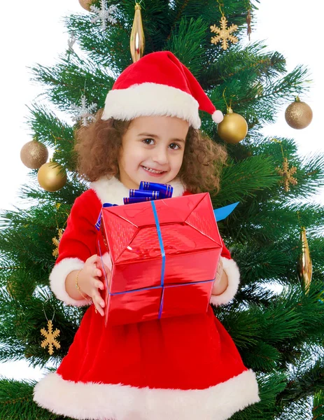 Bambina vicino all'albero di Natale con un regalo in mano — Foto Stock