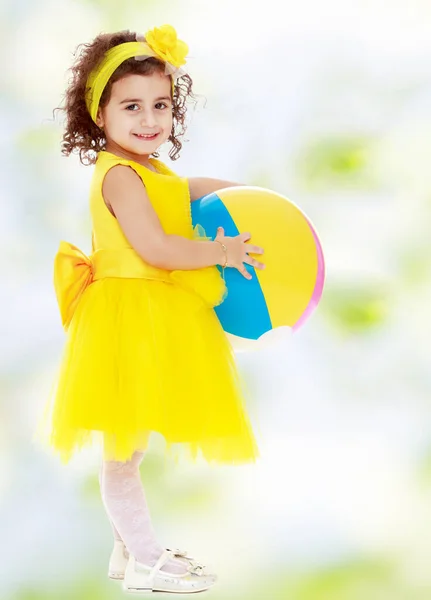 Kleines Mädchen im gelben Kleid mit großer Kugel — Stockfoto