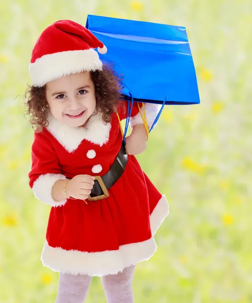 Menina em traje de Papai Noel com pacotes coloridos — Fotografia de Stock