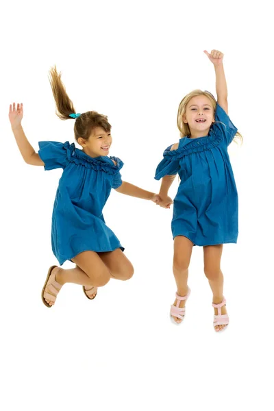 Two happy girls jumping holding hands — Stock Photo, Image