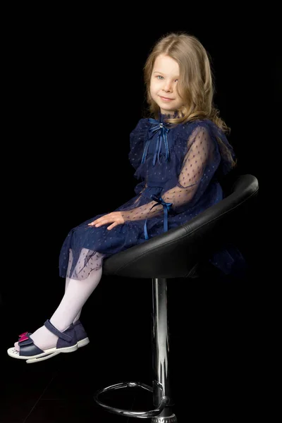 Boční záběr holčičky sedící na vysoké barové stoličce Royalty Free Stock Obrázky