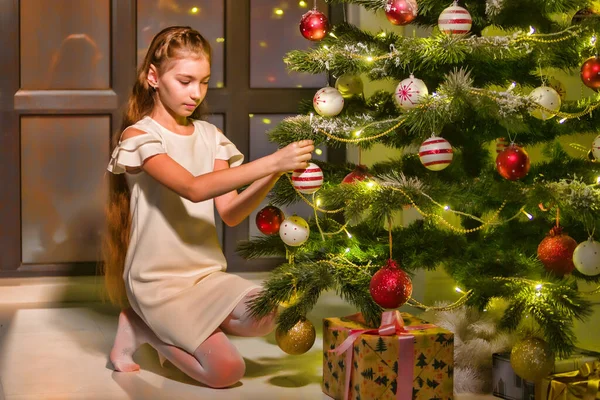 A menina decora uma árvore de Natal. Conceito de Ano Novo, férias em família. — Fotografia de Stock