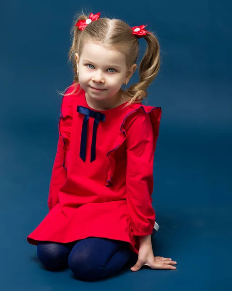 Urocza dziewczynka w czerwonej sukience siedzi na kolanach — Zdjęcie stockowe