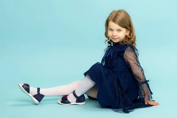 Gelukkig klein meisje in blauw jurk zitten op de vloer — Stockfoto